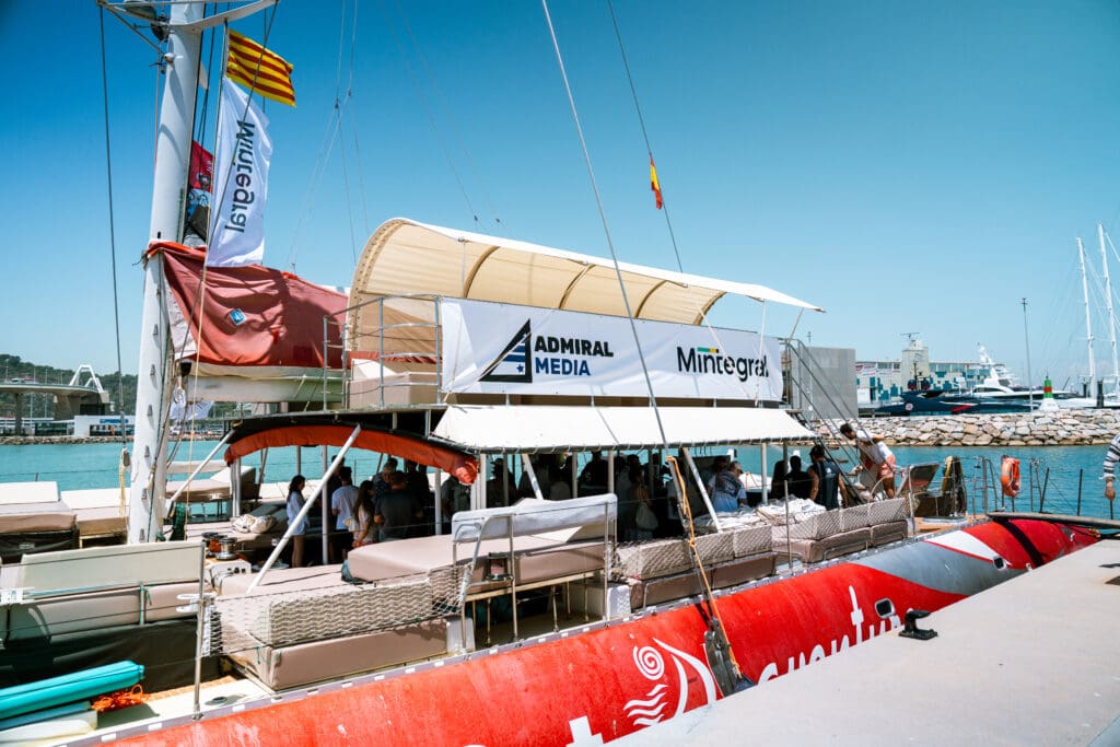 Guests gathering at the marina under an Admiral Media and Mintegral branded canopy before departure.