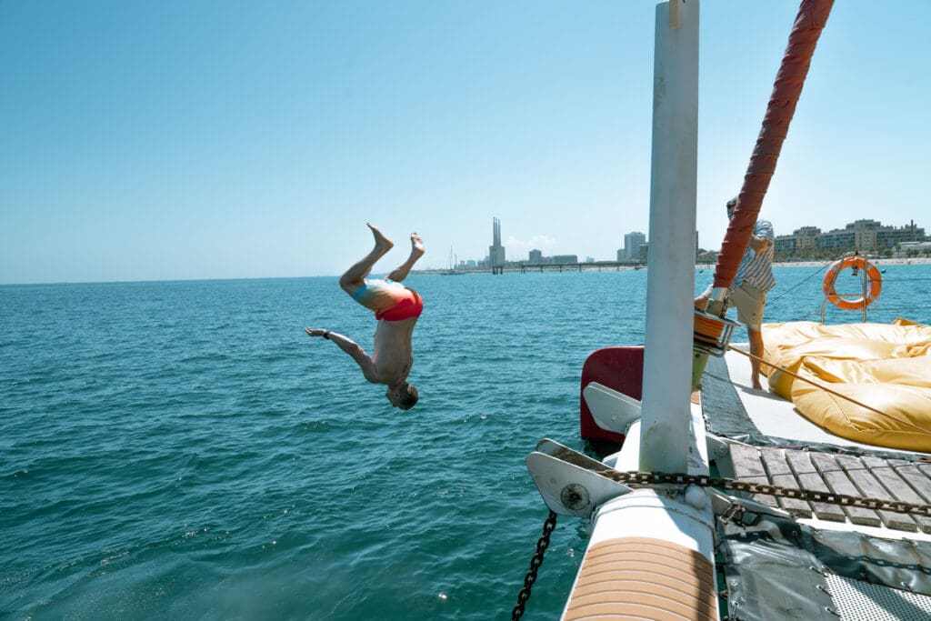 A guest mid-dive, inverted in the air off the side of the boat.