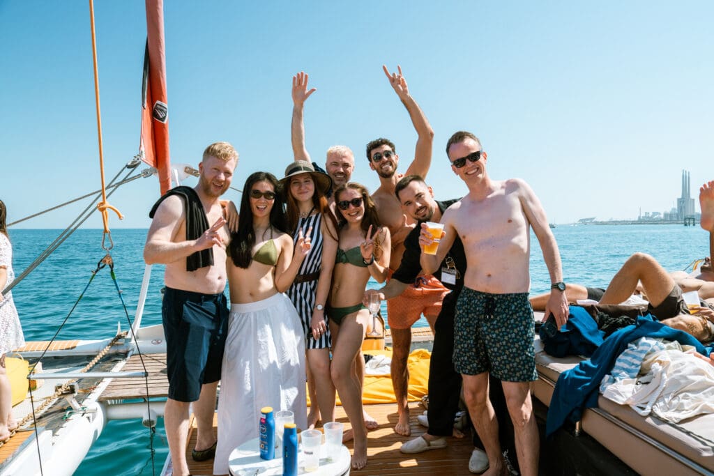 A group of guests cheering with their arms up on the bow of the catamaran.